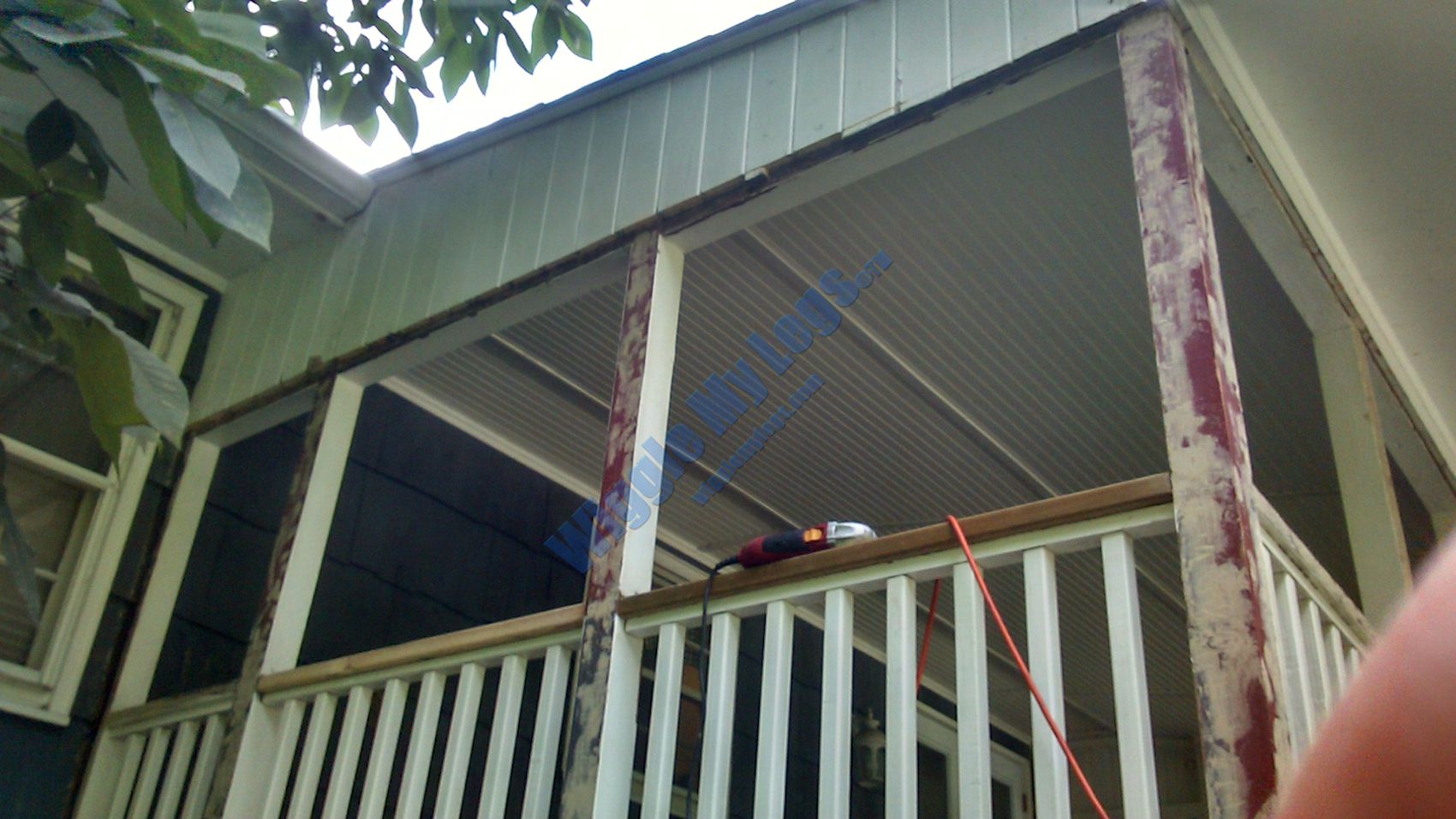 Gable with bottom edge of rotting shiplap siding being sawed off to make room for new frame for screens and remove rot.